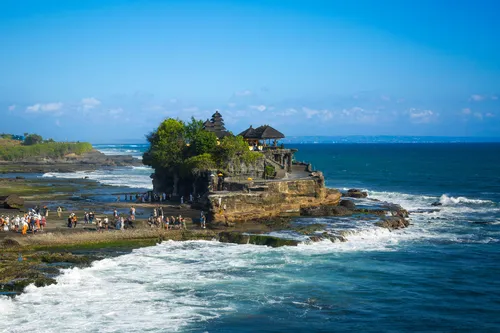 Tanah Lot Temple rising beautifully from the sea surrounded by crashing waves.